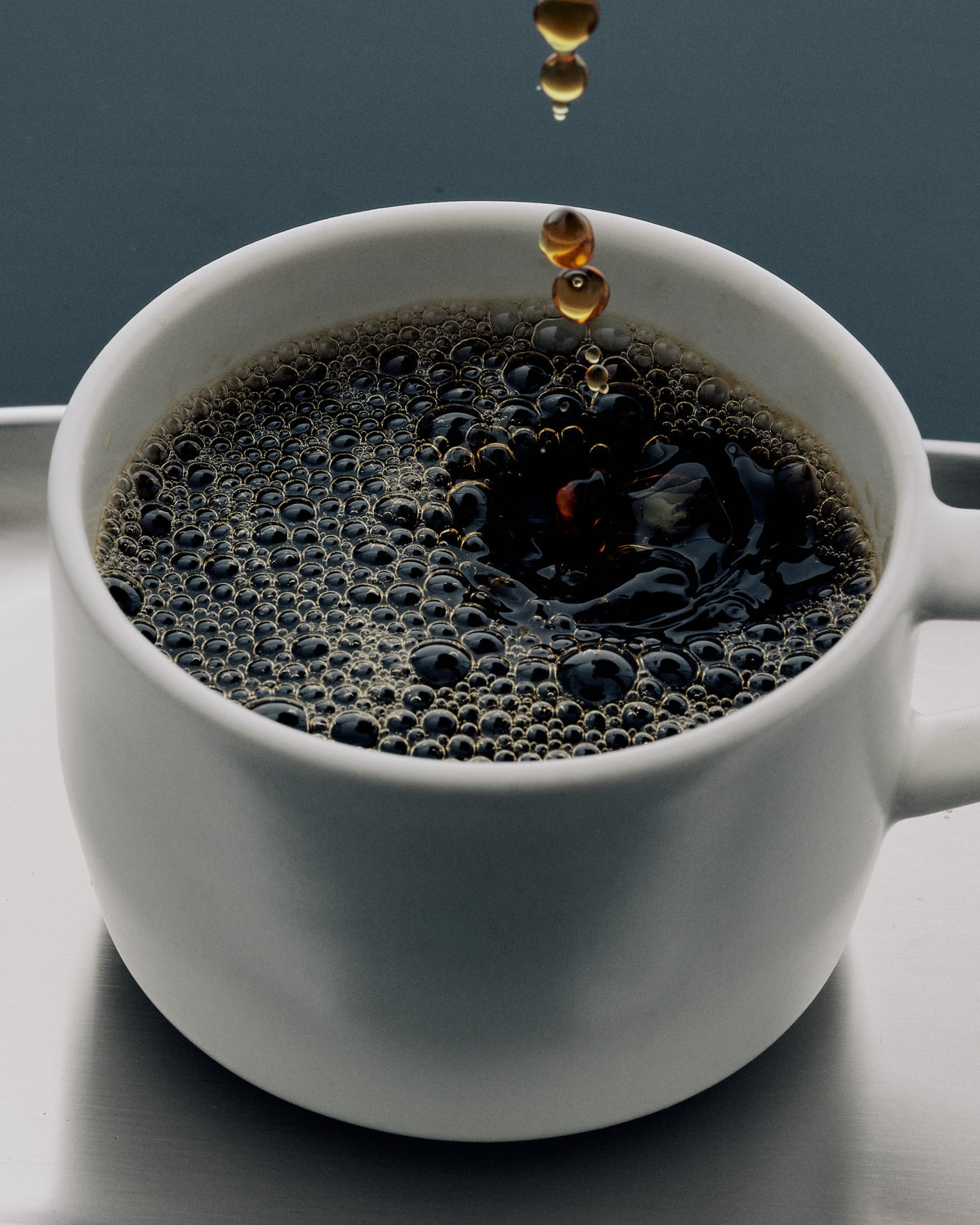 Freshly brewed black coffee dripping into a white cup